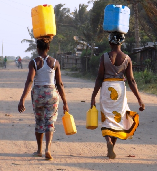 Mulheres carregando galões de água na cabeça.