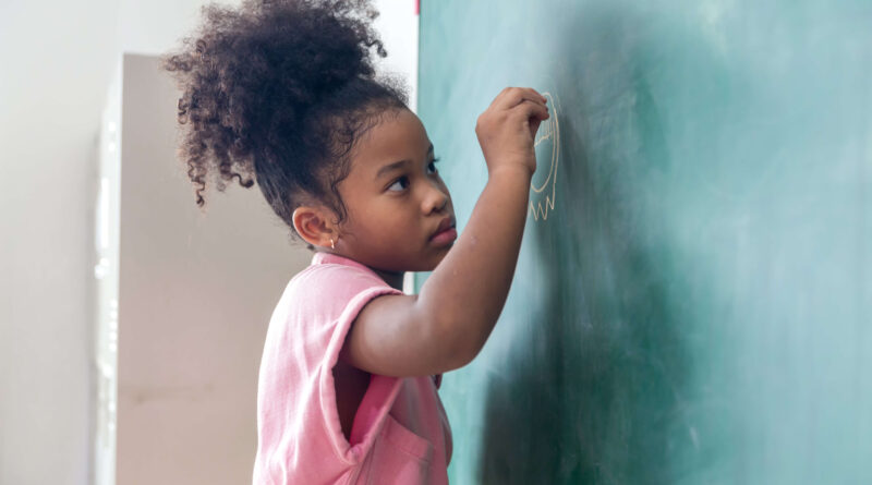 Menina negra escrevendo no quadro